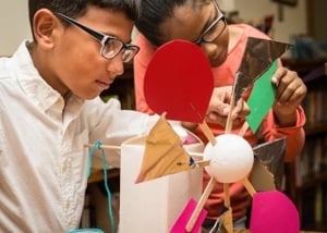 A young boy and girl engineer a model windmill